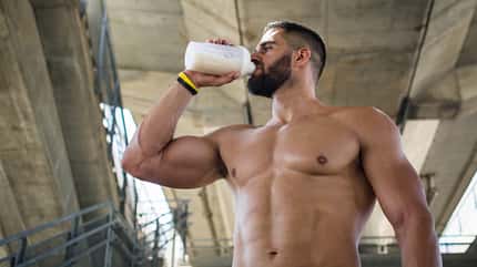 Ein Mann trinkt oberkörperfrei einen Proteinshake Ein Mann trinkt oberkörperfrei einen Proteinshake