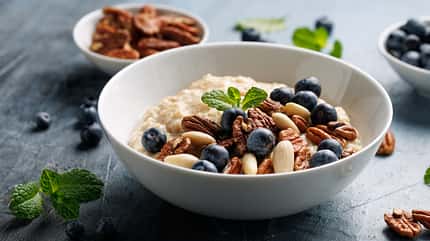Schale mit Porridge und Blaubeeren und Pekannüssen Schale mit Porridge und Blaubeeren und Pekannüssen