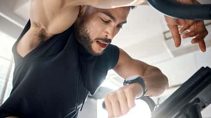 Ein Mann in Sportkleidung schaut auf seine Fitnessuhr Ein Mann in Sportkleidung schaut auf seine Fitnessuhr