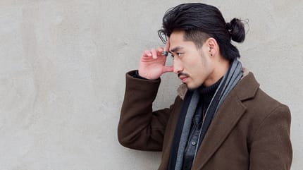Porträt eines chinesischen jungen schnurrbärtigen Mannes mit Undercut, der seine Hand an die Stirn legt