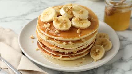 Delicious,Pancakes,With,Bananas,,Walnuts,And,Honey,On,White,Marble