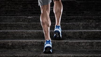 Sicht auf männliche Waden von hinten, während der Mann eine Treppe hochläuft Sicht auf männliche Waden von hinten, während der Mann eine Treppe hochläuft