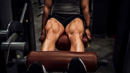 Ein Mann, der im Gym Beinübungen durchführt Ein Mann, der im Gym Beinübungen durchführt