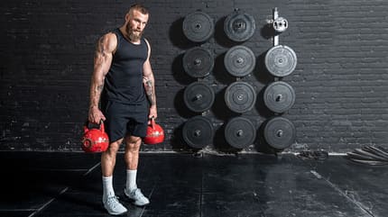 Ein Mann trainiert mit zwei Kettlebells Ein Mann trainiert mit zwei Kettlebells