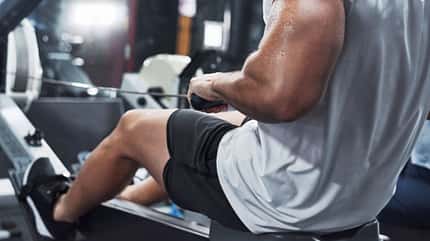 Ein Mann von hinten an der Rudermaschine im Gym Ein Mann von hinten an der Rudermaschine im Gym