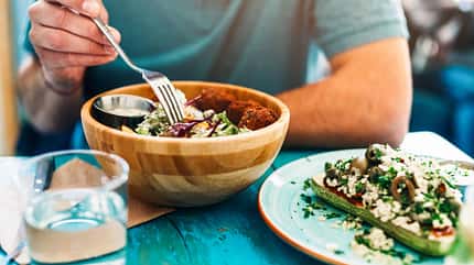 Ein Mann isst gesunde Salatbowl