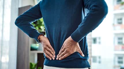 Mann fasst sich an den Rücken Mann fasst sich an den Rücken