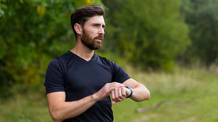 Sport Caucasian man looking smart watch at modern track runner using use smartwatch fitness bracelet Portrait fit male athlete checking result jogging in sportswear in street urban city park outdoor