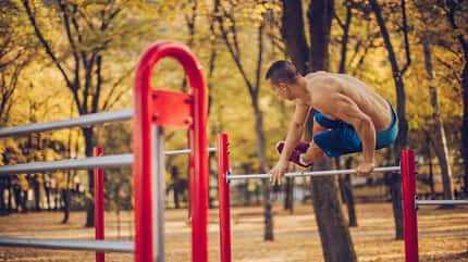 Ein Mann macht Calisthenics-Übungen im Park Ein Mann macht Calisthenics-Übungen im Park