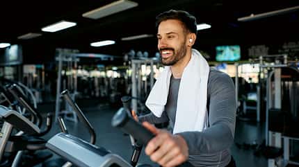 Smiling sportsman exercising on elliptical cross trainer in gym Smiling sportsman exercising on elliptical cross trainer in gym