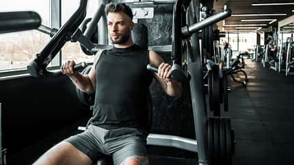 Fitter junger Mann, der Gewichte im Fitnessstudio stemmt