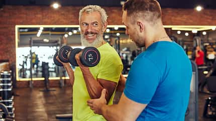 Ein Trainer verbessert die Haltung eines Mannes beim Krafttraining