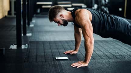 Ein Mann trainiert im Fitnesscenter die hohe Planke Ein Mann trainiert im Fitnesscenter die hohe Planke