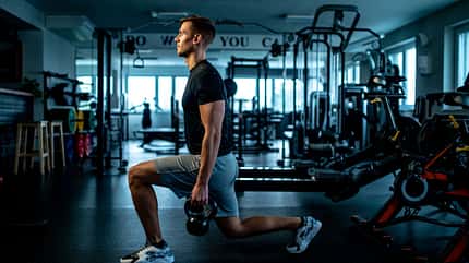 Young man Practicing Walking lunge with Kettle bell