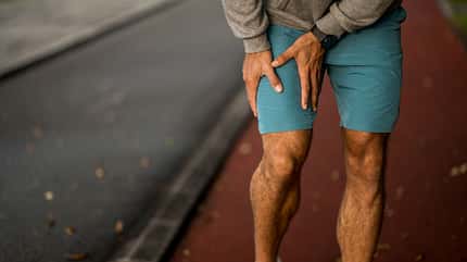 Ein Mann hält sich beim Laufen an sein schmerzendes Bein