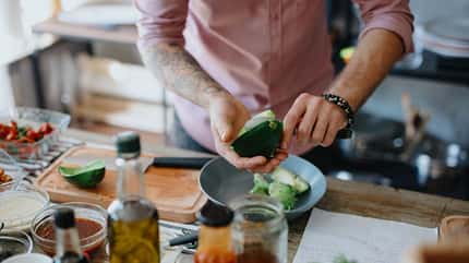 Ein Mann, der eine Avocado aufschneidet Ein Mann, der eine Avocado aufschneidet