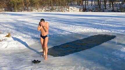 Ein Mann in Badehose nach dem Eisbaden auf dem Eis