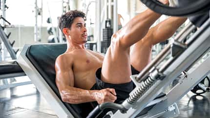 Healthy lifestyle, exercising and people concepts. Muscular man doing leg presses on leg press machine in the gym. Healthy lifestyle, exercising and people concepts. Muscular man doing leg presses on leg press machine in the gym.