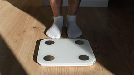 Mid adult man step on weight scales at home Mid adult man step on weight scales at home