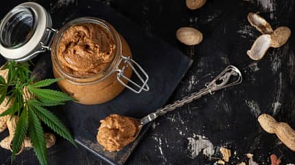 Erdnussbutter mit Cannabisöl auf dunkelm Hintergrund