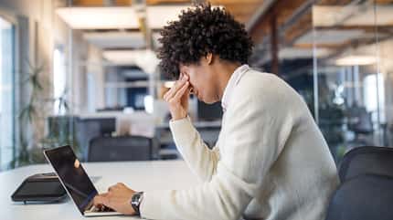 Ein müder Mann beim Arbeiten, der sich angestrengt an die Stirn fasst