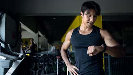 Young Asian sport men check the sports watches after exercising.