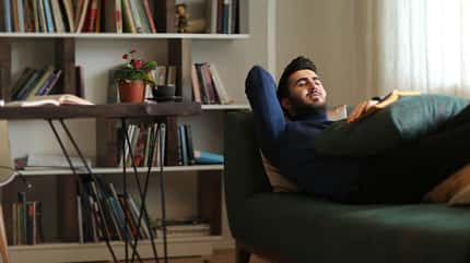 Ein Mann liegt nach der Arbeit erschöpft auf dem Sofa Ein Mann liegt nach der Arbeit erschöpft auf dem Sofa