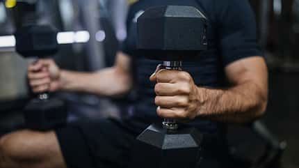 Ein Mann trainiert mit zwei Kurzhanteln