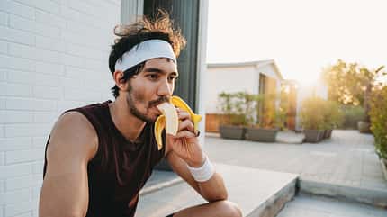 A tennis player is eating a banana during a break A tennis player is eating a banana during a break