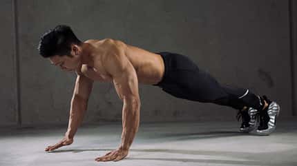 Mann hält eine Plank-Position in modernem Raum Mann hält eine Plank-Position in modernem Raum