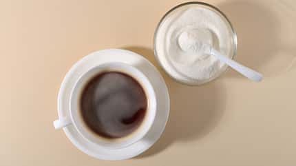 Nahrungsergänzungspräparat neben einer Kaffeetasse auf beigem Hintergrund