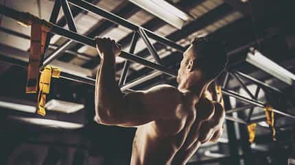 Trainierter Mann macht Klimmzüge im Fitnessstudio
