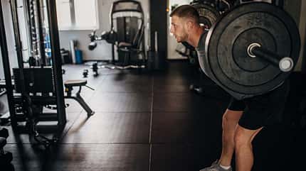 Ein Mann, der allein im Fitnessstudio mit Gewichten trainiert.