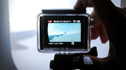 Closeup einer Actionkamera, die durch ein Flugzeugfenster filmt