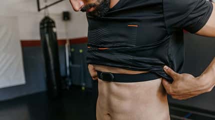 Ein Mann zieht sein Sportshirt hoch und schaut herunter auf sein sichtbares Sixpack
