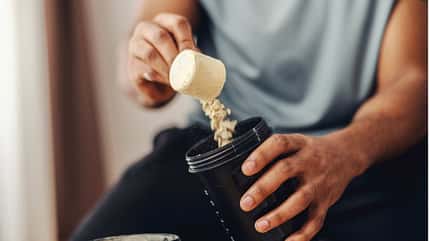 Ein Mann fügt Proteinpulver zu seinem Shaker hinzu Ein Mann fügt Proteinpulver zu seinem Shaker hinzu