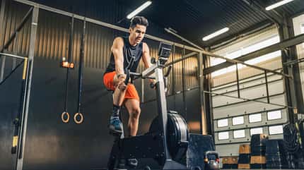 Männlicher Athlet, der auf dem Fahrrad im Fitnessstudio trainiert.