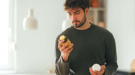 Mann hält zwei Pillendosen in den Händen und schaut auf die Rückseite des Produktes Mann hält zwei Pillendosen in den Händen und schaut auf die Rückseite des Produktes
