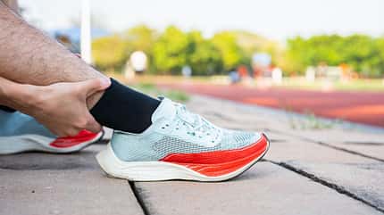 Mann fasst sich an die Wade, hat Laufschuhe an Mann fasst sich an die Wade, hat Laufschuhe an