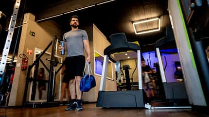 Ein Mann kommt mit Sporttasche im Fitnesscenter an Ein Mann kommt mit Sporttasche im Fitnesscenter an