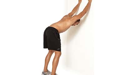 Beidarmiges Brustdehnen mit gestreckten Armen an der Wand Beidarmiges Brustdehnen mit gestreckten Armen an der Wand