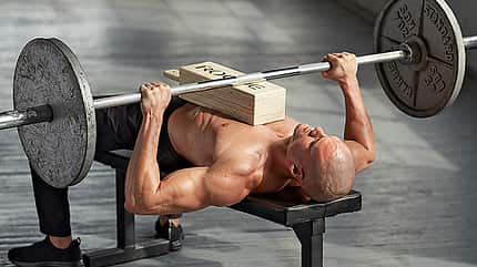 Beim Bankdrücken unterstützt ein Yogaklotz auf Brust und Bauch Beim Bankdrücken unterstützt ein Yogaklotz auf Brust und Bauch