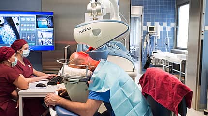 Der Haartransplantations-Roboter bei der Arbeit an den Haarfollikeln Der Haartransplantations-Roboter bei der Arbeit an den Haarfollikeln