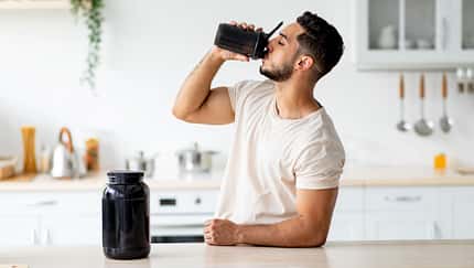 Young,Arab,Guy,Drinking,Protein,Shake,From,Bottle,At,Kitchen,