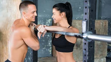Sportliche Frau flirtet im Gym mit einem durchtrainierten Mann