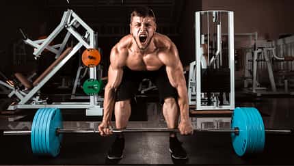 Mann beim Deadlift rinkt sichtbar nach Kraft