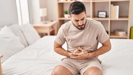 Mann hält sich den Bauch vor Schmerzen.