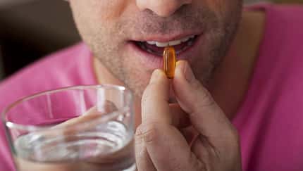 Mann schluckt ein Omega-3-Supplement.