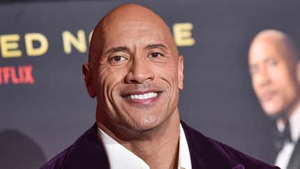 Dwayne Johnsons Gesicht vor dem Hintergrund eines Filmplakats. 