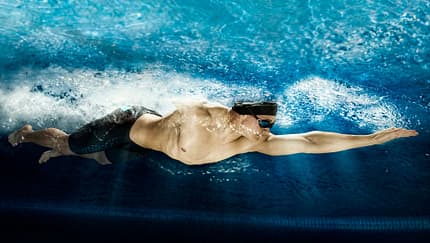Mann krault athletisch durch einen Pool 